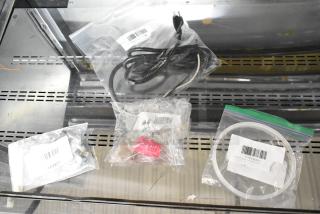 Five new scratch and dent items including Avantco 177PCMAD1 tank gasket, Amana 12002453 handle kit, Frymaster 8101831 gas pilot assembly, Avantco 177PCMAD11 power cord, all in sealed bags with labels.