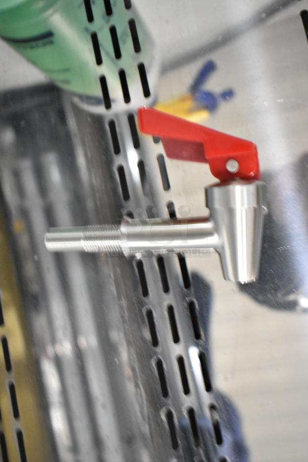 Metal valve handle with shiny finish and red lever, mounted on a perforated metal surface.