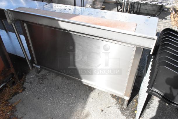 Stainless steel table with backsplash and under shelf, used condition, sturdy legs, industrial quality for kitchen use.