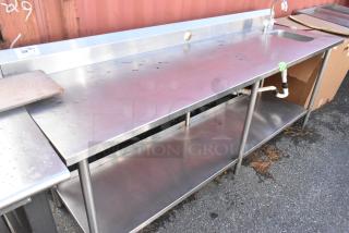 Stainless steel table with sink bay, back splash, and under shelf. Visible wear, includes faucet and drainage pipes. Lot tag 302.