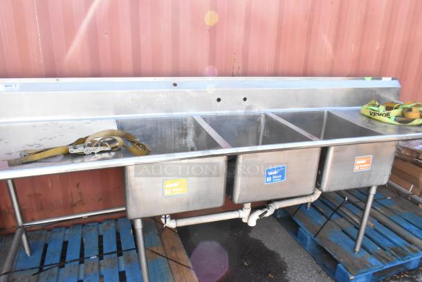 Stainless steel 3 bay sink with dual drain boards, labeled "1 Wash," "2 Rinse," and "3 Sanitize," in used condition.