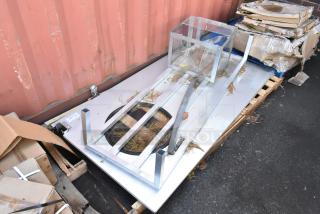 Four brand new scratch and dent items including a metal swinging kitchen door and a metal dunnage rack on a pallet.