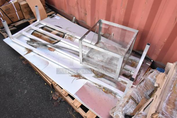 Four brand new scratch and dent items: metal swinging kitchen door and metal dunnage rack, on a pallet.