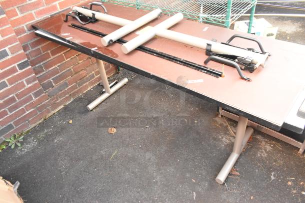 Two foldable tables with metal legs, laid on ground. Used condition, some scratches visible. Ideal for indoor/outdoor use.