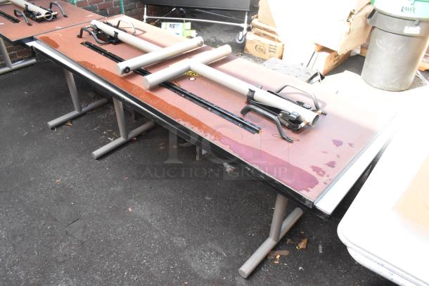 Two rectangular tables with metal legs, showing signs of wear. Items are placed on top, highlighting their durability.