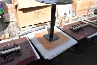 Two white tables with black metal bases, some water stains and marks visible; cardboard box labeled "Regency" in background.