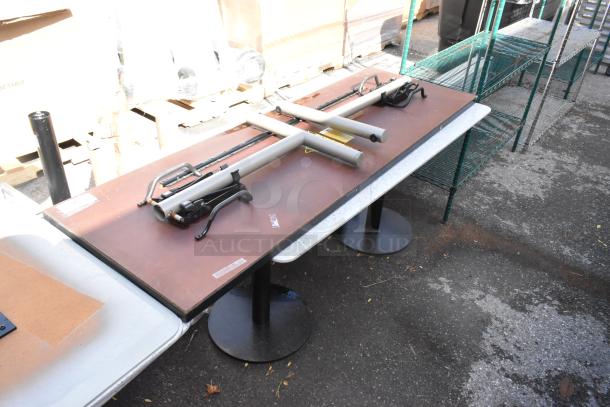 Two tables with sturdy metal bases and rectangular tops. Additional components are placed on top. Suitable for commercial use.