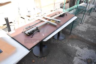 Two tables with sturdy metal bases and rectangular tops. Additional components are placed on top. Suitable for commercial use.