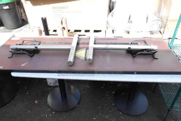 Two foldable tables with metal legs, placed upside down. Includes a safety label. The tables appear lightly used.