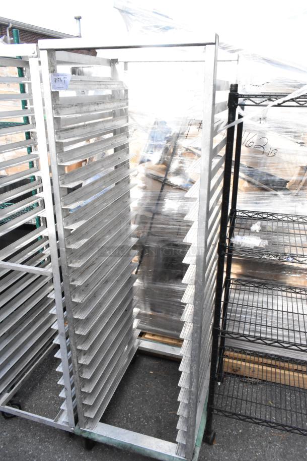 Metal commercial pan transport rack on casters, featuring multiple slots for pan storage. Good condition with visible tag.