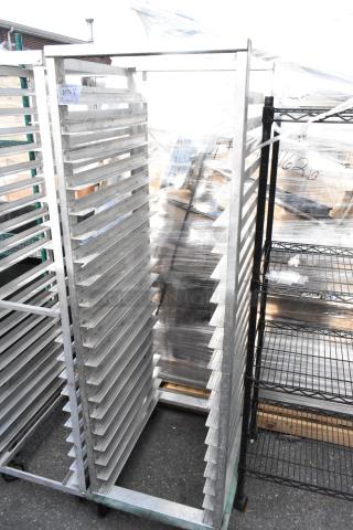 Metal commercial pan transport rack on casters, featuring multiple slots for pan storage. Good condition with visible tag.