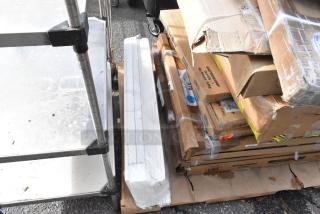 11 scratch and dent items, including Regency and Steelton stainless steel work tables, stacked in original packaging, some slight box damage visible.