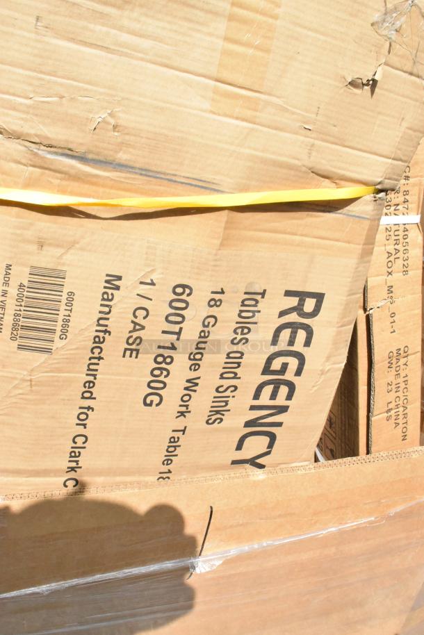 Pallet containing boxed Regency 18" x 60" stainless steel work table, scratch and dent condition, with visible packaging damage.