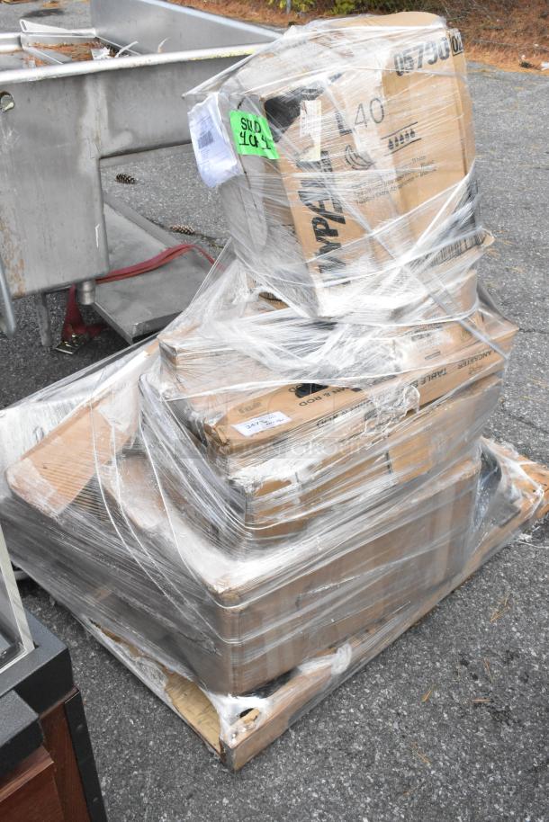 Pallet of 13 brand new scratch and dent Lancaster table bases and columns, wrapped in plastic, visible labels with item codes.