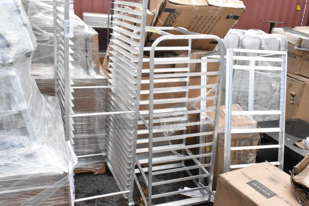 Lot of three brand new metal pan racks, minor scratches and dents visible. Includes slotted shelves and sturdy frame.