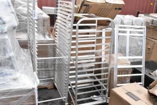Lot of three brand new metal pan racks, minor scratches and dents visible. Includes slotted shelves and sturdy frame.