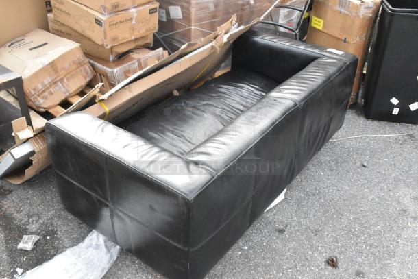 Black couch with armrests, leather-like material, some visible wear; includes minor scuffs. In used condition, auction item.