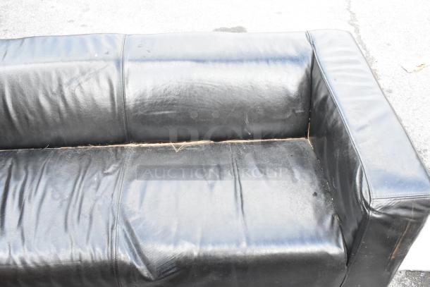 Black couch with armrests, visible wear, and creases. Cushion seams show signs of age. No visible tags or labels.