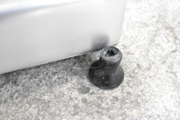Close-up of a Globe G10 metal meat slicer foot, showing wear from use on a countertop surface.