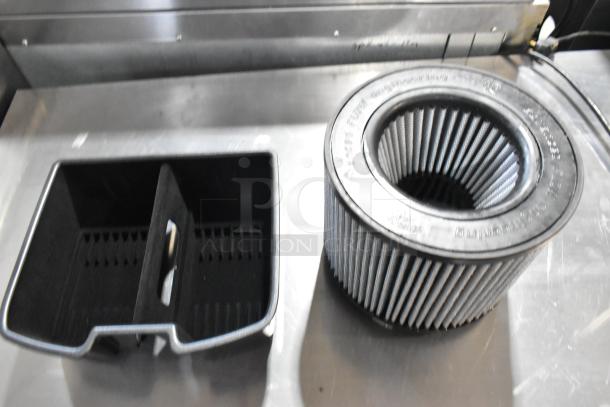 Two items: cylindrical air filter with ribbed design and rectangular black plastic piece with compartments. Both in good condition.