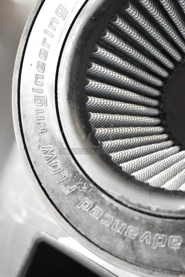 Air filter with "engineering" marking, featuring a pleated design and black rubber rim. Part of a two-item auction.