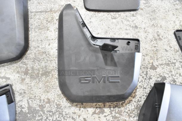 Box of GMC-branded automotive mud flaps in two black poly bins, in good condition with visible part numbers.