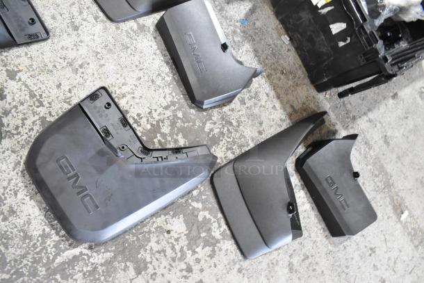 Box of GMC vehicle parts in black poly bin, featuring logos and various shapes, in good condition. Suitable for repairs.