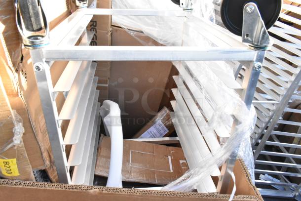 Lot of brand new scratch and dent items, including a metallic pan rack, shelf, and tabletop, wrapped in protective plastic.