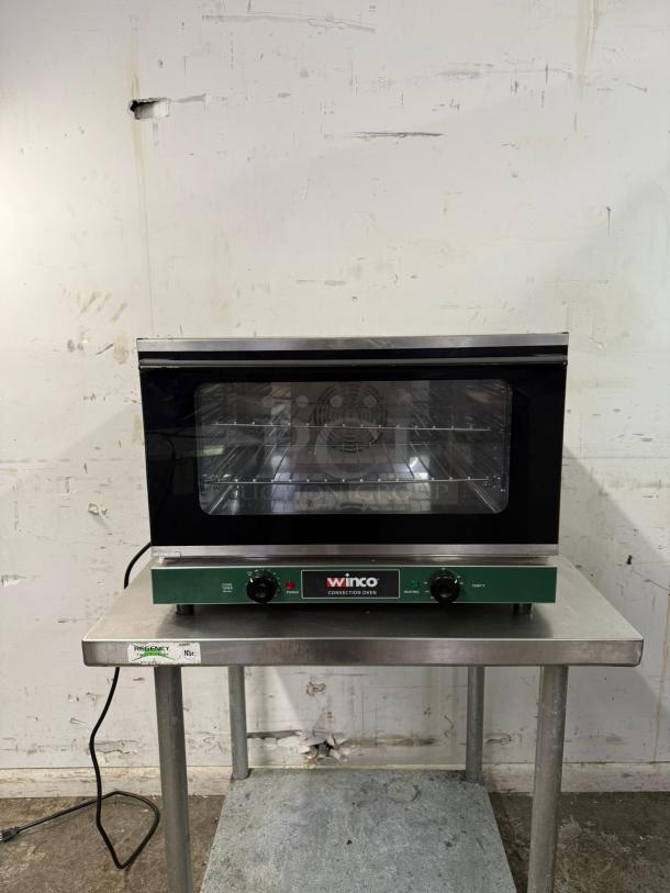 WINCO half-size countertop convection oven, 120v, with two control knobs, in used condition on a metal table.