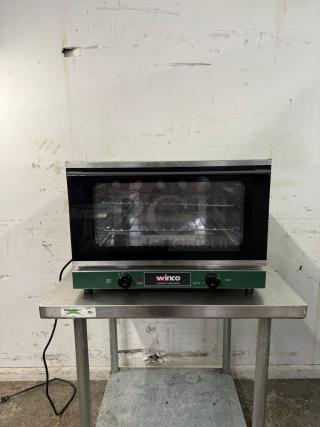 WINCO half-size countertop convection oven, 120v, with two control knobs, in used condition on a metal table.