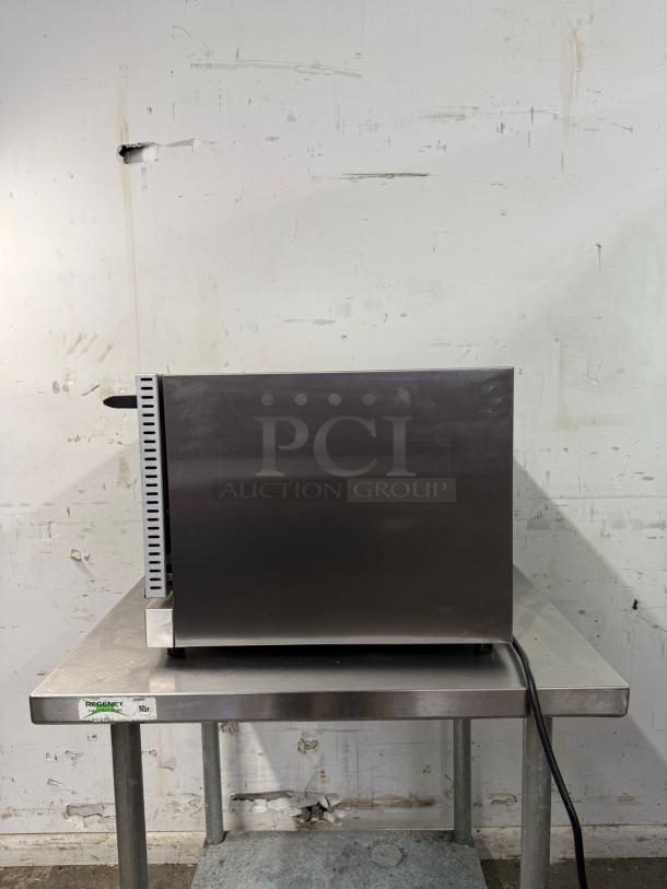 WINCO half-size countertop convection oven, 120v; stainless steel, side view on table; shows power cord.