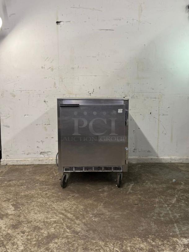 UNDER COUNTER 28" refrigerator, stainless steel, on wheels, visible label, appears in good condition.