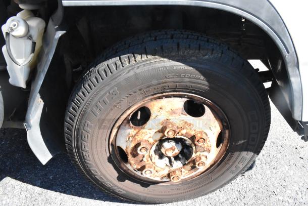 Close-up of the rear tire on a 2004 Izuzu Morgan Diesel Reefer Box Truck. Visible rust on the wheel rim.