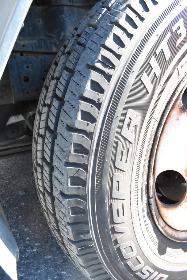 Close-up of a 2004 Isuzu Morgan Reefer Truck tire. Visible tread and "HT3" marking. Rust on the wheel rim.