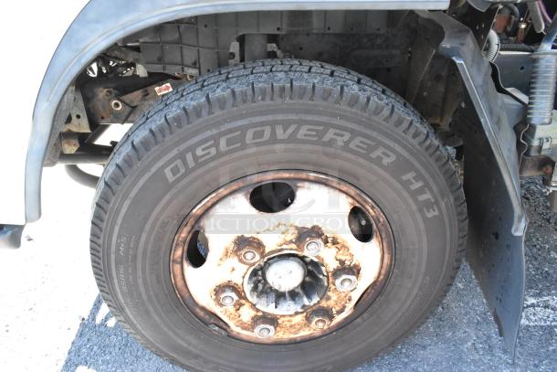 2004 Isuzu Morgan Diesel Reefer Box Truck, close-up of Discoverer HT3 tire on rusted wheel with Carrier Transicold system.