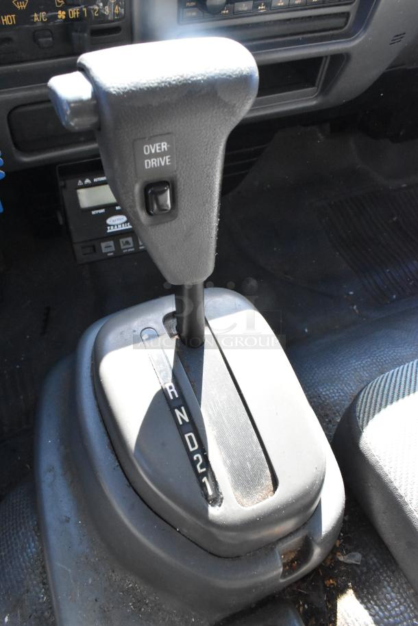 Gear shift of 2004 Izuzu Morgan Diesel Reefer Box Truck with visible overdrive button, showing wear. Odometer reads 215,769.