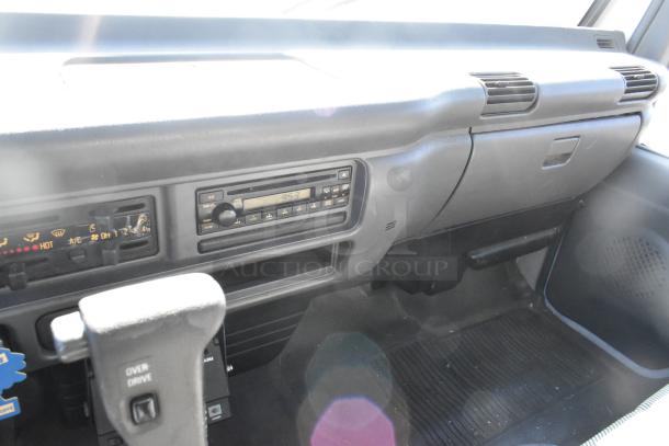 Interior dashboard of 2004 Isuzu Morgan Diesel Reefer Box Truck, showing CD player, vents, and gear shift labeled "Over Drive."
