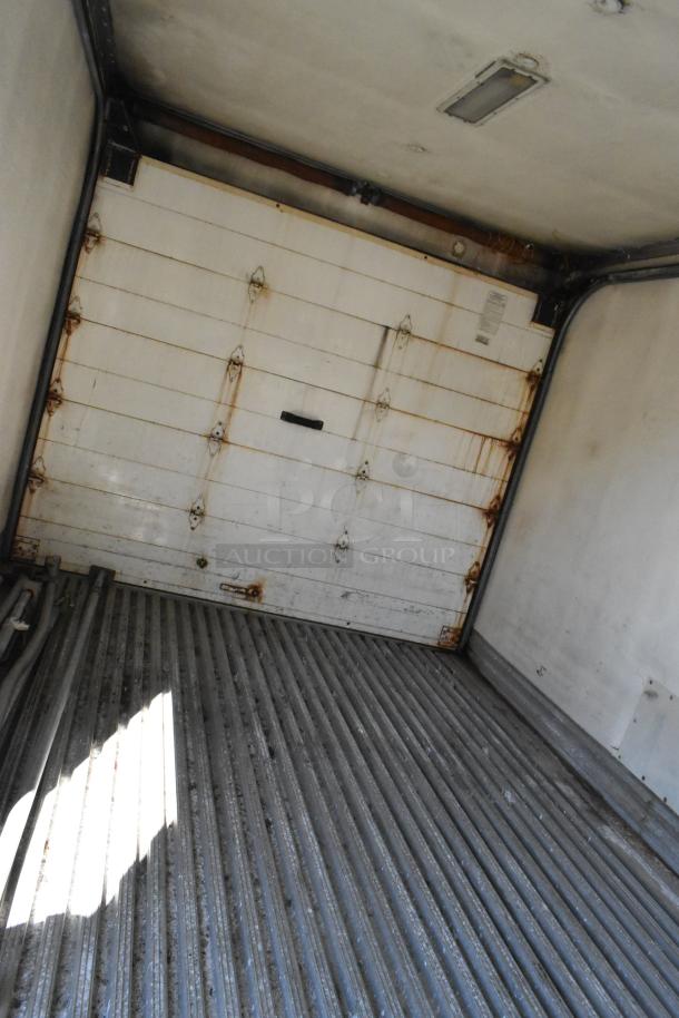 Interior view of a 2004 Isuzu Morgan Diesel Reefer Box Truck. Features a ribbed metal floor and a rear door with visible rust.