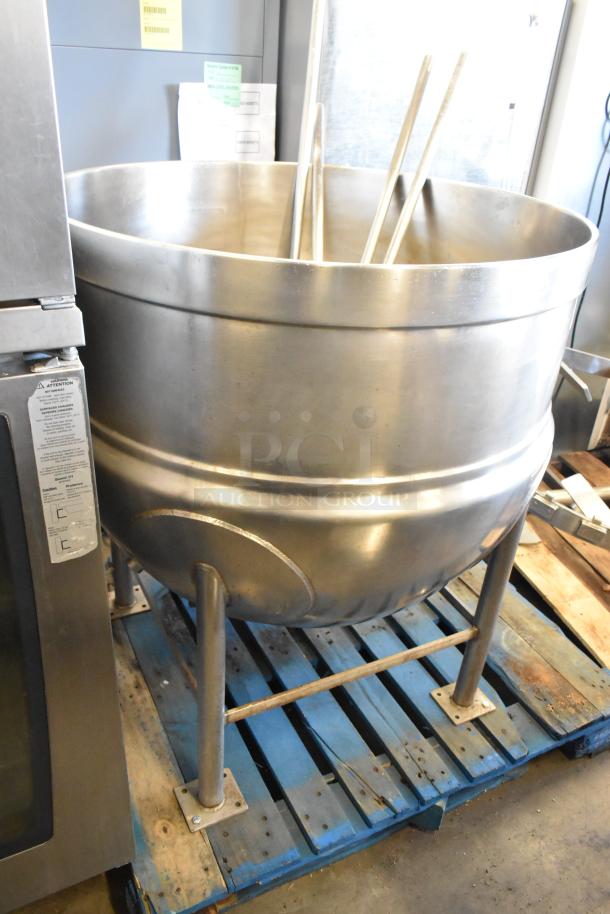 Stainless steel commercial floor-style kettle with agitator on pallet, in used condition, features sturdy legs and control panel.