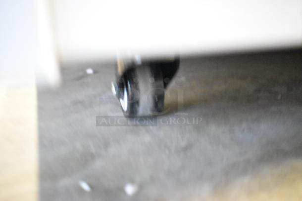 Blurred close-up of a caster wheel of the Avantco 193VOA70W commercial merchandiser.