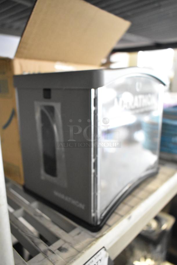 Brand new Marathon 6407124 interfold napkin dispenser. Slight cosmetic scratches, durable gray casing, visible branding.