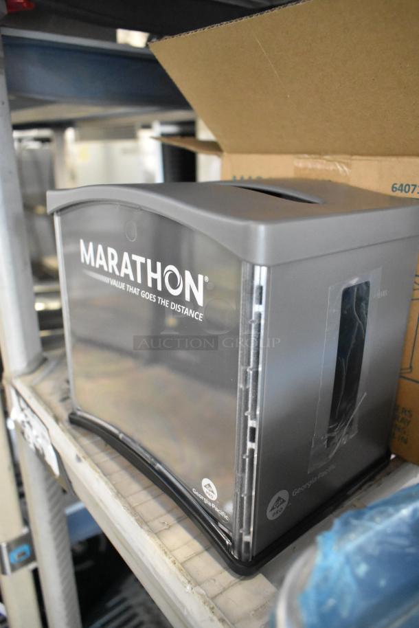 Marathon 6407124 Interfold Napkin Dispenser, brand new, minor scratches. Grey, with logo and "Value that goes the distance" text.