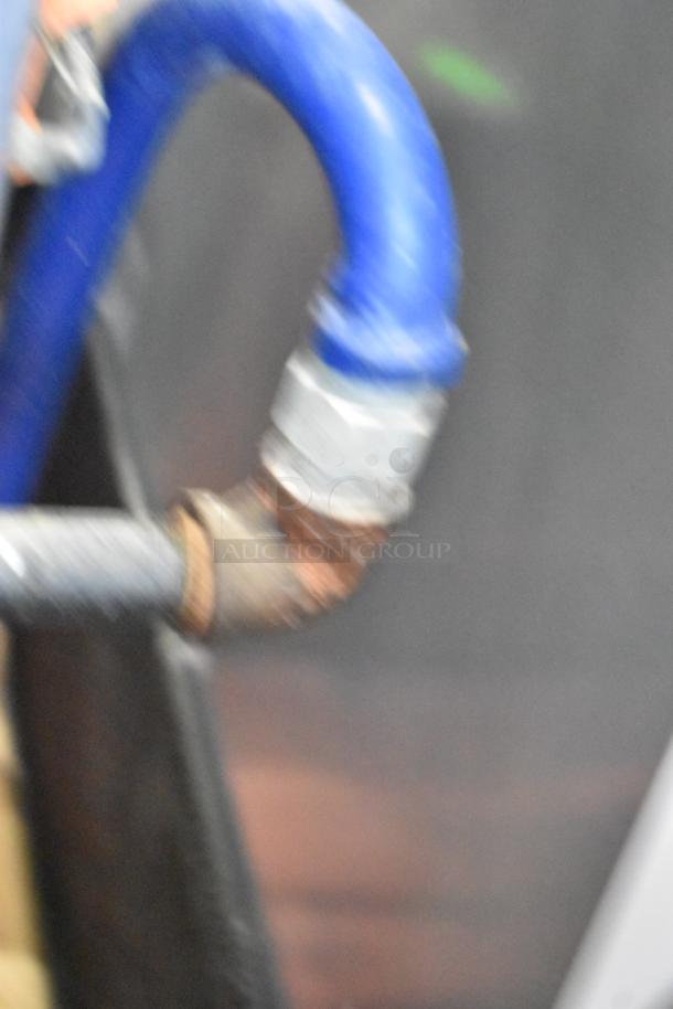 Close-up of a blue gas hose connected to a Hobart HGC5-11D3 commercial oven, showing part of the metal fitting.