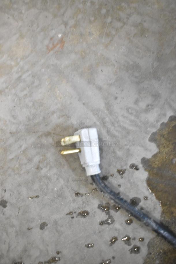 Electrical plug for True GDM-41SL-60-LD cooler, 115 volts, 1 phase connection, on concrete floor with some water droplets.