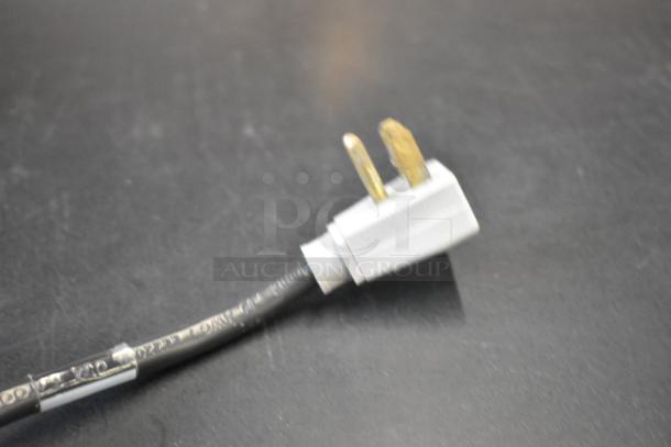 Close-up of a power plug for a True GDM-41SL-48-HC-LD commercial cooler, showing prongs and cable with visible markings.