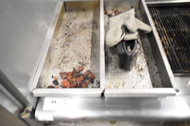 APW Wyott stainless steel gas charbroiler grill with grill grates and cleaning tools, showing signs of use.
