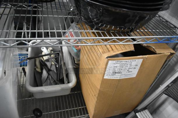 Metro lot including various plates, bowls, and a poly bin. Box with label for stretch film. Items stored on metal shelving. Shelving unit not included.