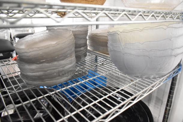 Metro lot of translucent plates, bowls, and a poly bin on metal shelving. Shelving unit not included. Suitable for various uses.