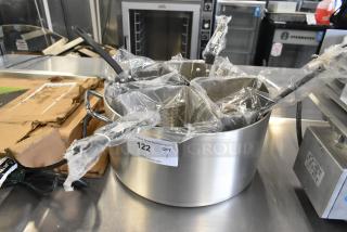 Brand new scratch and dent metal stock pot with 4 steamer baskets, wrapped in plastic. Auction tag number 122 visible.