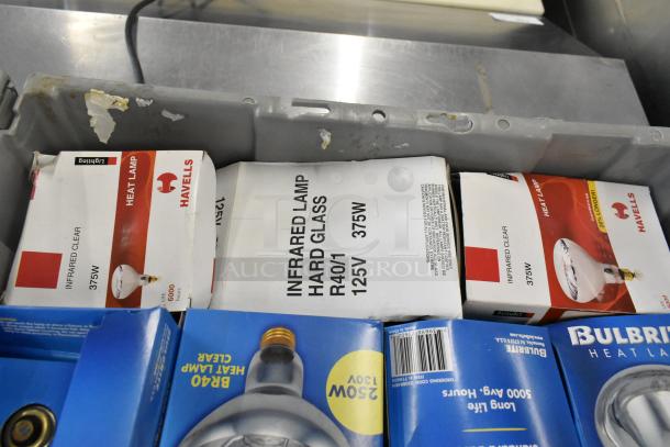 Brand new lot of Havells and Bulbrite infrared heat lamps in original packaging, stored in a gray poly bin.